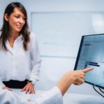 Doctor pointing at a computer screen while a patient looks on.