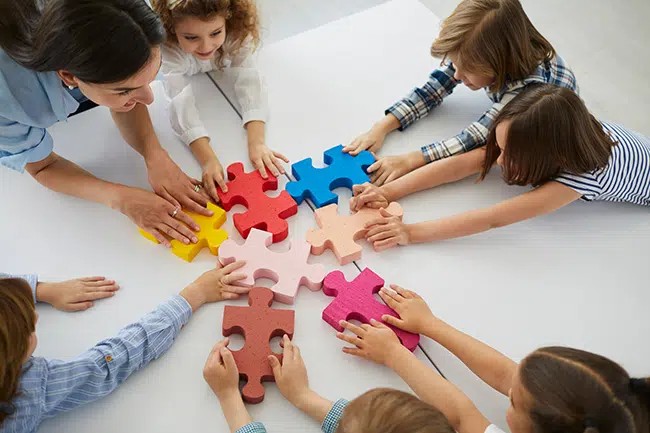 teacher and preschoolers putting together a puzzle