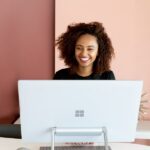 Smiling woman sitting behind a Microsoft-branded computer.